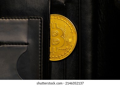 a bitcoin coin in a wallet. black leather pocketbook. close-up