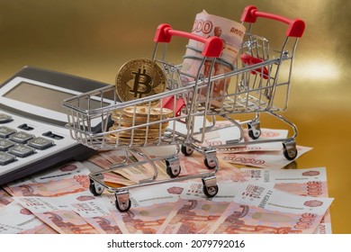 The Bitcoin Coins And Russian Rubles  In A Mini Carts From The Supermarket On Gold Background. Cryptocurrency Mining And Mining Concept.