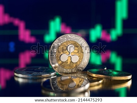 Bitcoin and cryptocurrency investing concept. Cryptocurrency golden coin with gold ripple symbol. Rise and fall charts of alt coins.