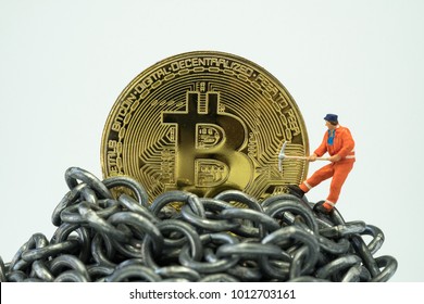 Bitcoin Mining Concept By Miniature Minor Worker, Small Mini Figure Holding Mattock Dig On Golden Physical Bitcoin Crypto Currency Coin On Top Of Metal Chains Or Block Chain Financial Money System.