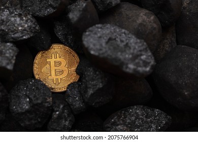 Bitcoin mining concept. Gold bitcoin cryptocurrency coin in a pile of coal