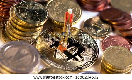 Bitcoin mining: Miner figurine digging ground to uncover big shiny bitcoin. Cryptocurrency concept with miner and coin working in bitcoin mine. Golden bitcoin Euro background.