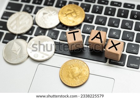 Bitcoin and next to wooden with TAX letters. Bitcoin taxation concept
