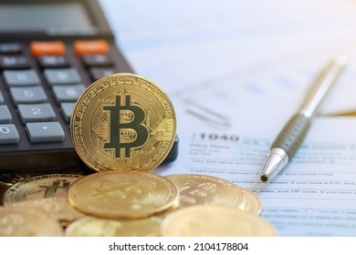 Bitcoin on a calculator and individual income tax return form 1040. tax for the trading of crypto-currencies.The time to pay taxes concept. - Shutterstock ID 2104178804