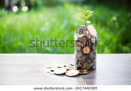 Bitcoin and other coins in a glass bottle are placed on a wooden table and the morning sun shines. There are many coins in the piggy bank. Concept money digital currency. Close-up, blurred background