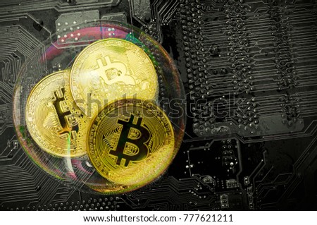 Bitcoin in a soap bubble on pc board background. Concept of an economic (financial, speculative) bubble. Dangers and risks of investing to bitcoin. Top view.