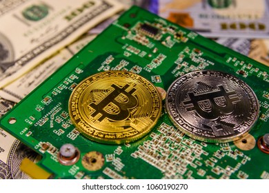 Bitcoins and circuit board on one hundred dollar bills