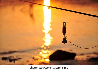 Premium Photo  Silver fishing bells are worn on a fishing rod while  fishing. bite-call signal, at the tip of the rod. a bite alarm will alert  you to a bite. fishing tackle close-up.
