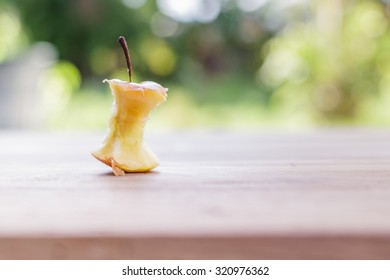 Bite apple on wooden table with nature background.