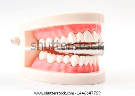 Bite the bullet, stoic attitude or endure an unavoidable painful or unpleasant situation concept theme with teeth biting on a silver bullet isolated on white background