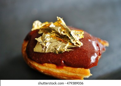 Bite Of A Chocolate Eclair Pastry With An Edible Gold Leaf On Top