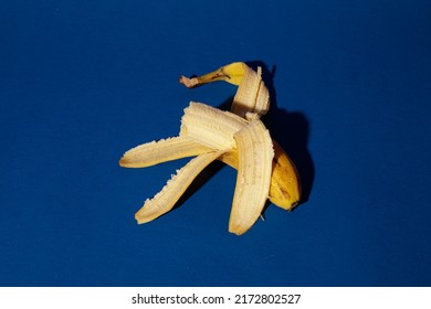 A bitten banana lies on a dark blue background. Nobody. Insulation. Healthy food. Fruit. Fitness. Diet. Proper nutrition. Bright fruit on a dark background