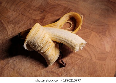 A bitten banana on a wooden board.