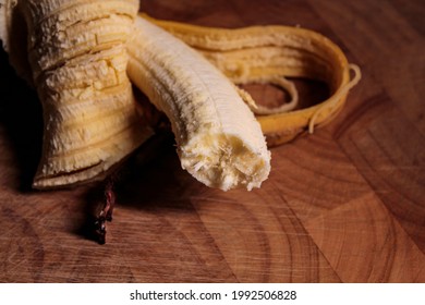 A bitten banana on a wooden board.