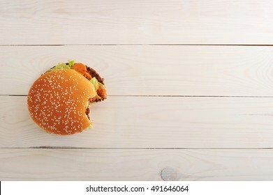 Bitten Bbq Hamburger With Vegetables, Spices On Wooden White Background. Top View With Copy Space For Text Menu