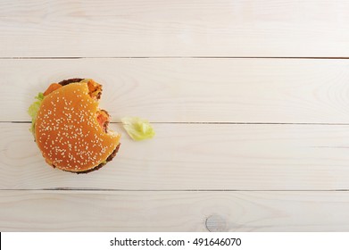 Bitten Bbq Hamburger With Vegetables, Spices On Wooden White Background. Top View With Copy Space For Text Menu