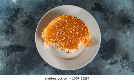 Bitten Burger On Plate On Gray Table, Top View. Fast Food.