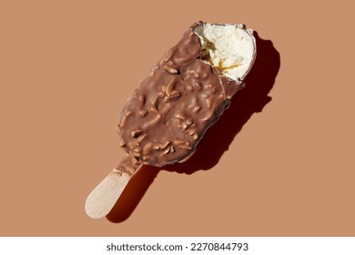 Bitten chocolate ice cream on a stick brown pastel background