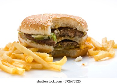 Bitten hamburger with french fries over white