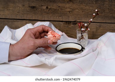 Bitten macaroon сake in hand. Breakfast concept in bed.