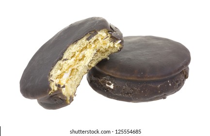 A Bitten Moon Pie Against A Full Size Chocolate Pie On A White Background.