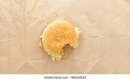 Bitten Off  Burger On Paper Background. Top View
