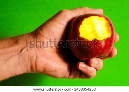 Bitten Red Apple on Hand on a Colred Background