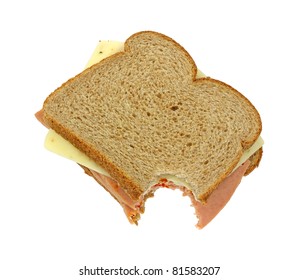 A Bitten Wheat Bread Sandwich With Pickle And Pimento And Pepper Jack Cheese On A White Background.