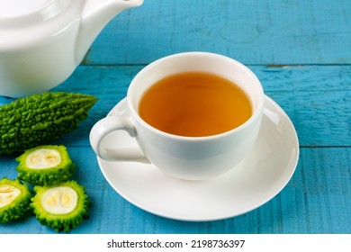 Bitter Gourd Or Bitter Melon Tea In White Cup On Blue Wooden Background. Scientific Name Is Momordica Charantia. As A Whole Food And Herbs For Treating Diseases.