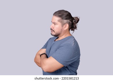 A bitter man in his 30s looking sideways with a scowling face and arms crossed. Jealousy, displeasure or pettiness. - Shutterstock ID 2201581213