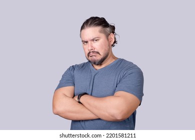 A bitter man in his 30s looks at the camera with a scowling face and arms crossed. Jealousy, displeasure or pettiness. - Shutterstock ID 2201581211