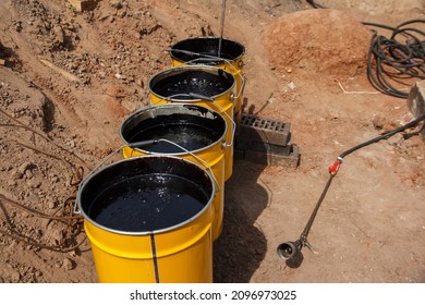 Bitumen mastic in buckets. Protective bitumen mastic for concrete pavement. Material for waterproofing the foundation.
