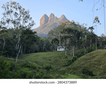 Bizarre image with a small white building in the middle of a pasture and forest and in the background it appears  Morro da Igreja. It is located between the municipalities of São Bento do Sul and Corupá in Santa Catarina, Brazil. The three characteristic stone resemble the shape of the towers and domes of an old church.