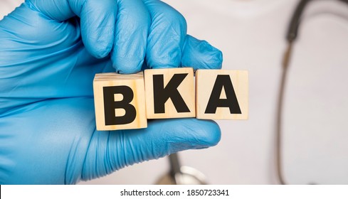 BKA Below the knee amputation - word from wooden blocks with letters holding by a doctor's hands in medical protective gloves. Medical concept.
