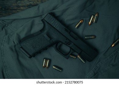 black 9mm pistol on a black gray fabric background with 9mm ammunition next to it. top view