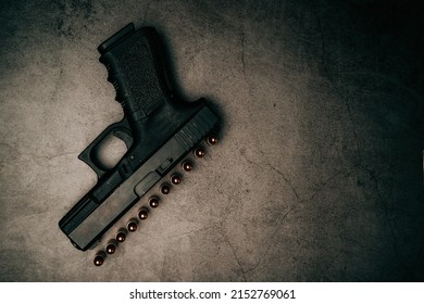 black 9mm pistol on an old concrete floor with 9mm ammunition next to it. top view