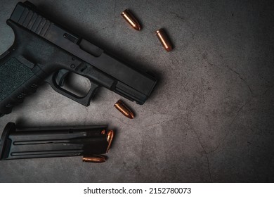 black 9mm pistol on an old concrete floor with 9mm ammunition next to it. top view