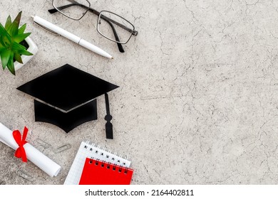 Black academic cap or graduation hat on students table, top view