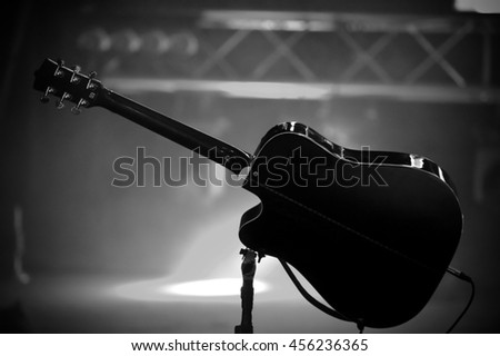Black acoustic guitar on the stage with soffits light