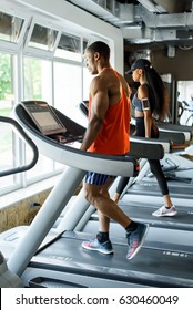 Black african american athletic couple running on treadmills in gym