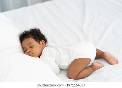 Black African American Baby Sleeping On A White Mattress.