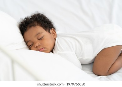 Black African American Baby Sleeping On A White Mattress.