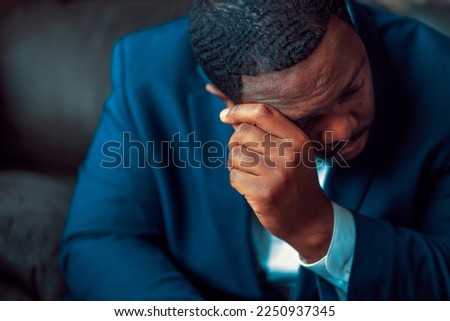 Black or African American business man sitting down looking anxious and depressed wearing blue suit