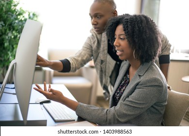 Black African American businesswomen or coworkers together in an office doing teamwork or job training.  The women are working together at a startup business. 