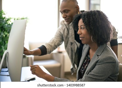 Black African American businesswomen or coworkers together in an office doing teamwork or job training.  The women are working together at a startup business. 