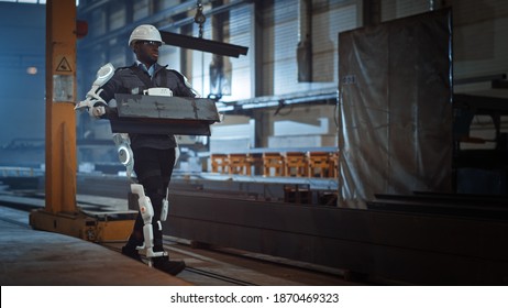 Black African American Engineer Is Testing A Futuristic Bionic Exoskeleton And Proudly Wearing It In A Heavy Steel Industry Factory. Powered Mobile Machine Shell Made For Helping Workers.