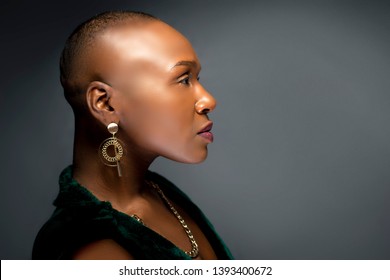 Black African American female fashion model with a bald hairstyle in a studio.  The portrait shows the beauty and confidence of the bold and trendy glamour hairdo style.  