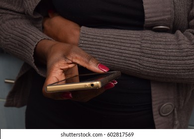 Black African Female With Red Nail Polish Using The Smart Phone