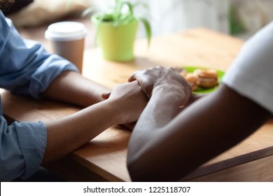 Black African Guy Holds Hand Of Beloved Girl, Sitting Together At Table Expressing Showing Her Sincere Feelings Or Apologizing Saying Sorry. Reliable Person, Trusted Friend, True Friendship Concept