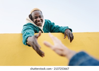 Black African Man helping caucasian friend offering hand to climb wall. Concept of, friendship, solidarity and support - Shutterstock ID 2137253667